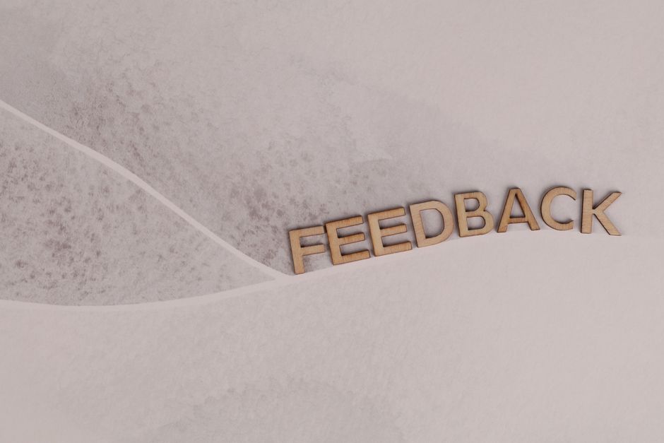 Wooden letters spelling 'FEEDBACK' arranged on textured paper background, conveying a conceptual theme.
